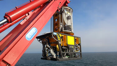 A hydrolic sea crane lowers some equipment into the ocean