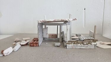 Building materials arranged to form a model of a basic building shape
