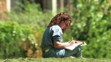 Girl sitting on grass, studying