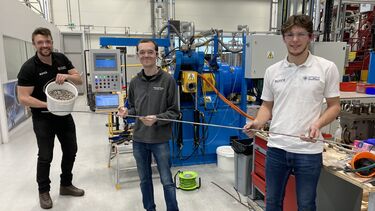 Three men holding wire in a lab