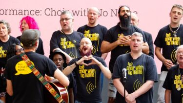 A choir performs in front of a guitarist at an event