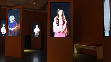 Photograph still from the One Song exhibition featuring different people on a number of screens