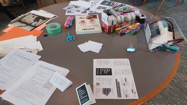 A range of materials e.g. scissors, markers, papers, on a table, which attendees could use for their zines. 