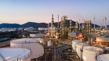 An aerial view of a petrochemical plant in the evening with a blue sky in the background