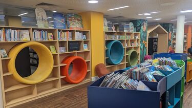 Book displays and shelves in Manchester Library with colourful circuluar cutouts in the shelves