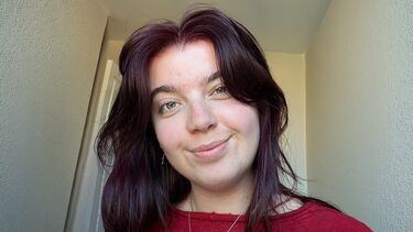 A young girl in a red shirt smiling 