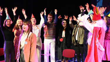 Scene from the Dutch play 2022 in which a group of characters cheer the lead character's birthday. St Nicolas is also present. 