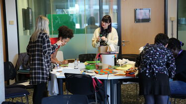 Students in a creative workshop decorating t-shirts and tote bags.