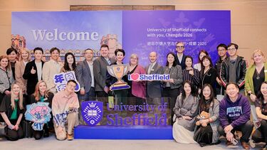 A large group of people standing in front of a purple University of Sheffield sign