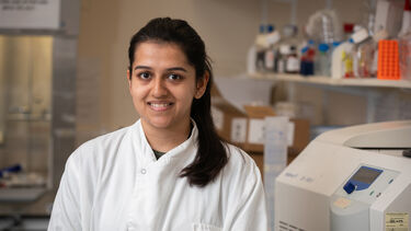 Image of Anusha, an MND researcher in the lab, wearing a lab coat