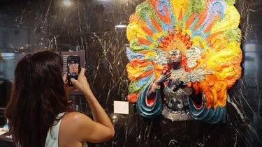  A visitor takes a photo with their phone of a colourful sculpture of a showgirl. 