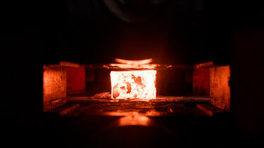 Red-hot glowing metal ingot between two rollers