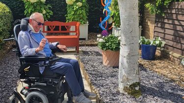 Man in a wheelchair outside in a garden.