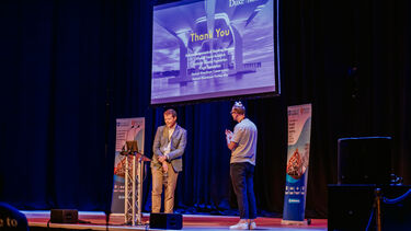 Engineers on a stage with a Thank You slide backdrop