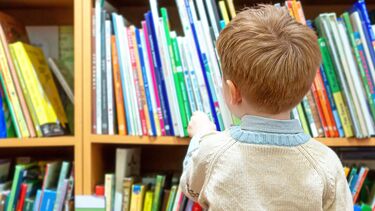A child picking a book from a shelf at a public library
