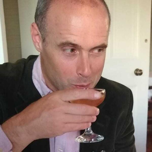 Profile picture of A photo of Dominic Gregory sipping a drink at a table.
