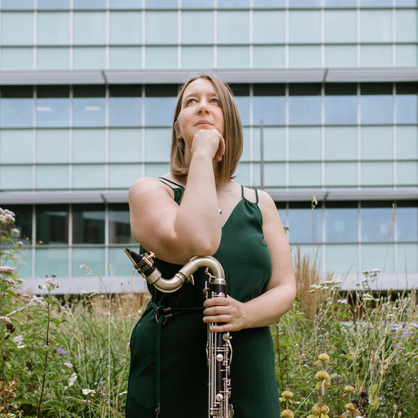 Profile picture of Sarah looks to the foreground, resting her arm on her clarinet.