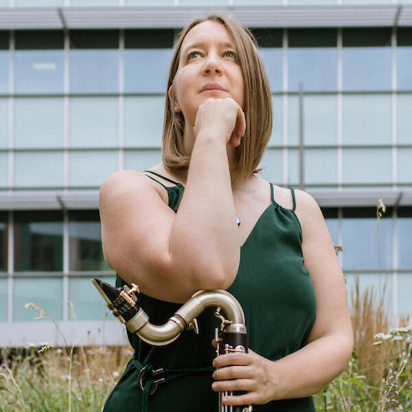 Profile picture of Sarah looks to the foreground, resting her arm on her clarinet.
