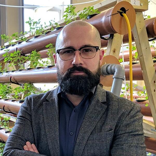 Profile picture of Jacob Nickles stood with crossed arms in front of a selection of small plants