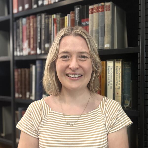 Profile picture of Kate stands in front of shelves of books 