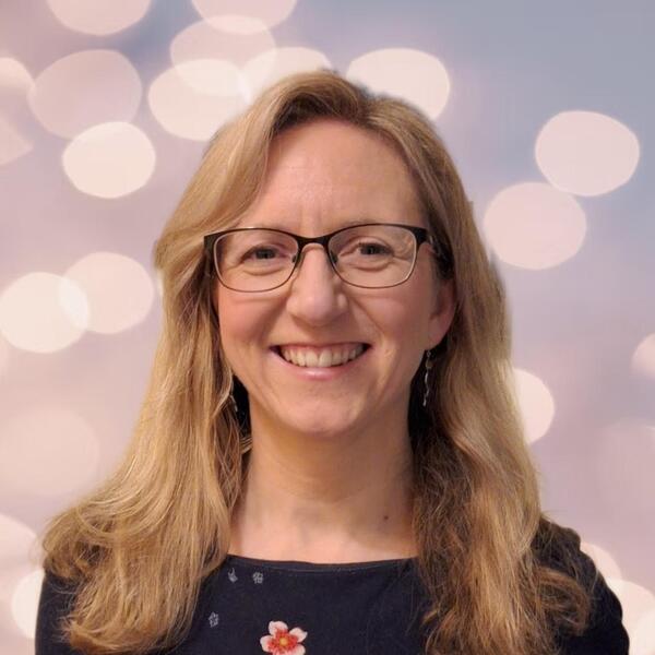 Profile picture of Megan smiles at the camera, with shoulder length blonde hair and wearing glasses