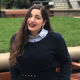 Loukia smiling, in front of the playing fields at the University