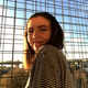 Image of SMI student Ellie, with a city landscape in the background.