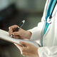 A photo showing a doctor writing on a clipboard