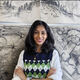 Landscape student smiling in front of charcoal drawings with arms crossed