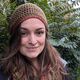 Student smiling surrounded by trees wearing hat and scarf