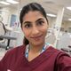Iram is in a dental teaching suite. She has dark hair which is tied back, and is wearing maroon scrubs.