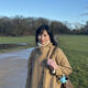Student smiling in sunny park wearing coat and gloves 