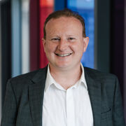 David Littlewood wearing a white shirt and dark grey jacket.