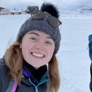 Charlotte Curry in a wooly hat, smiling in front of some snow