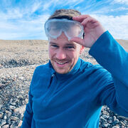 Jeremy Ely holding a pair of plastic safety goggles on his forehead