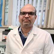 Manoj Menon in a lab standing next to some scientific equipment