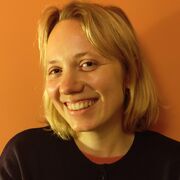 Mari- Liis standing in front of an orange wall smiling