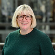 Headshot of a woman wearing a green jumper and glasses