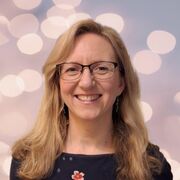 Megan smiles at the camera, with shoulder length blonde hair and wearing glasses