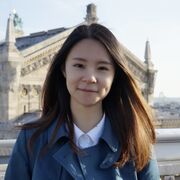 Nan (Elva) Peng smiles at the camera, with buildings in the background