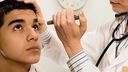 A doctor with a torch studying a patient's eyes for infection. 