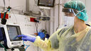 a person in a mask and protective gear operates a ventilator