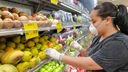 Woman wearing a mask in a supermarket and gloves. She is picking up an apple.