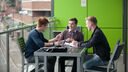 Three young men sitting at a table on a balcony