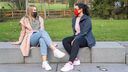 Two girls socialising on the steps with face coverings 