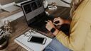 A woman working at desk with a laptop abd notepad