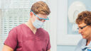 Two healthcare workers, one wearing a face shield