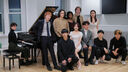 Group of students stood round the piano