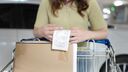A person reading a receipt whilst pushing a shopping trolley