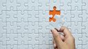A jigsaw with one final piece being added to the puzzle